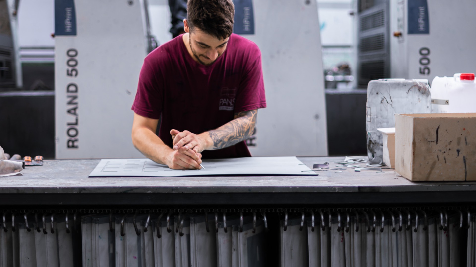 Offset printer marking up a plate in front of a Manroland Roland 500